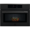 Electrolux KVM9E2XT в матово черно с включен дисплей и стъклен съд с храна зад затворената врата.