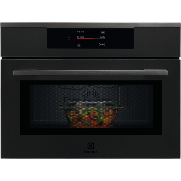 Electrolux KVM9E2XT в матово черно с включен дисплей и стъклен съд с храна зад затворената врата.